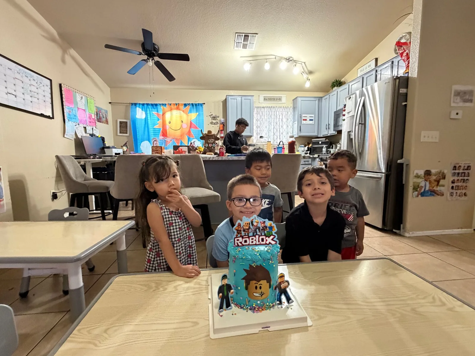The playroom at Angelita's Little Angels with tables, the kitchen and children celebrating a birthday