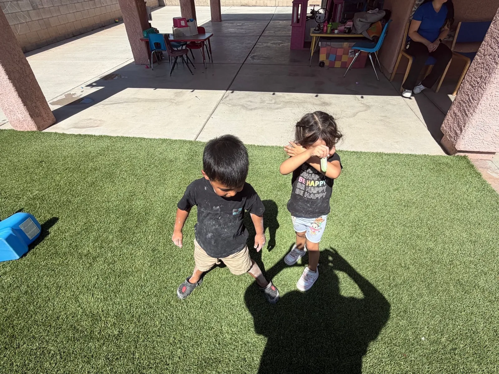 Children playing on the artificial turf in the covered backyard